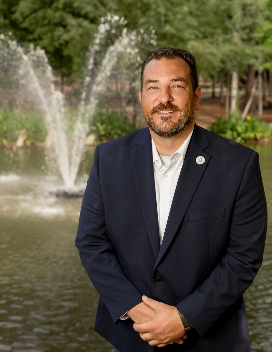 Gabriel Penfield in a navy blazer in front of a park fountain