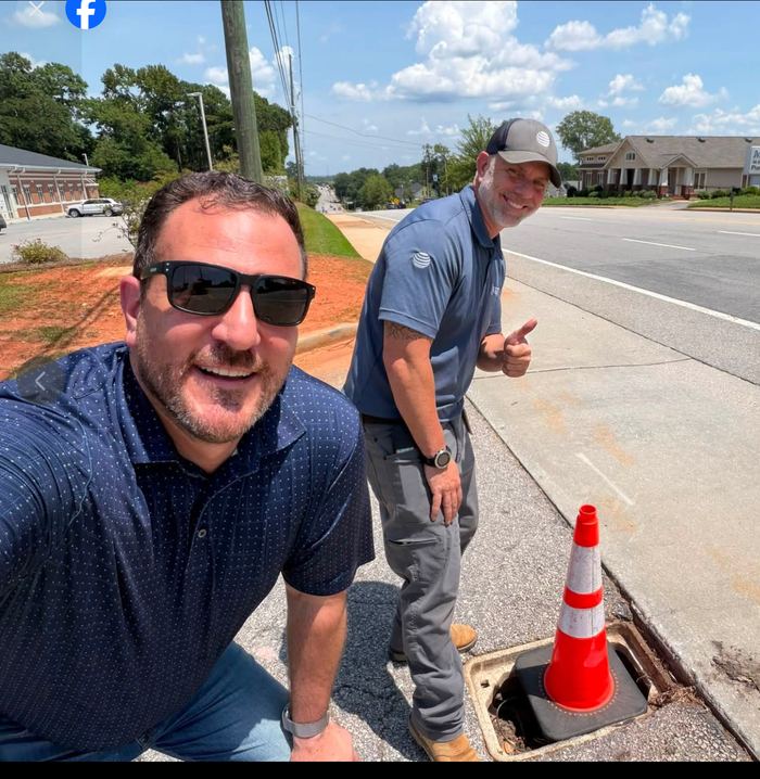 Gabe with an AT&T technician beside a coned-off utility box
