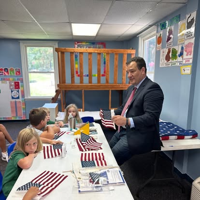 Students at a table covered with small American flags while Gabriel Penfield teaches